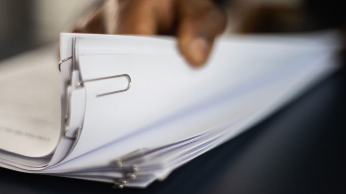 A person holding clipped documents related to a property dispute.