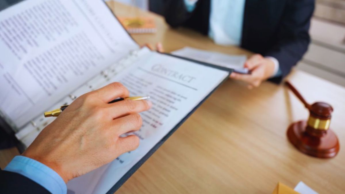 Lawyer assisting a client in contract law planning by reviewing and explaining legal documents; gavel visible on desk, representing legal guidance.