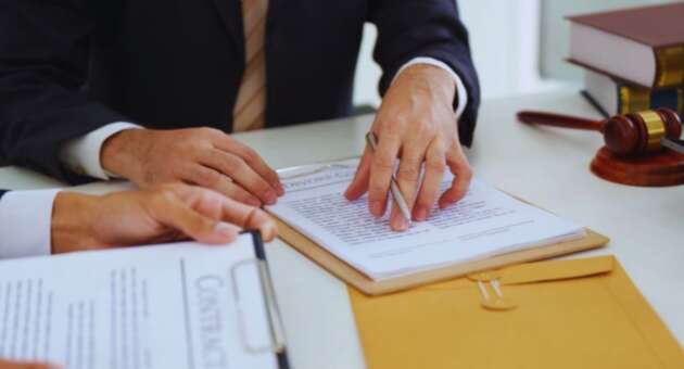 Lawyer reviewing and explaining contract documents with a client during contract law planning, focusing on legal terms, obligations, and dispute prevention, with a gavel and legal books on the desk.