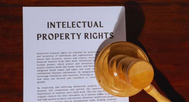 A document titled 'PROPERTY RIGHTS LAW' related to real estate ownership is displayed on a wooden surface, with a wooden judge's gavel resting on the lower right corner of the paper.