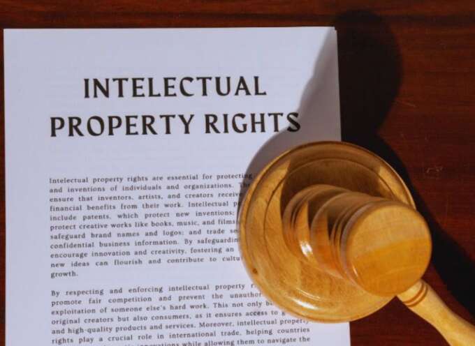 A document titled 'PROPERTY RIGHTS LAW' related to real estate ownership is displayed on a wooden surface, with a wooden judge's gavel resting on the lower right corner of the paper.