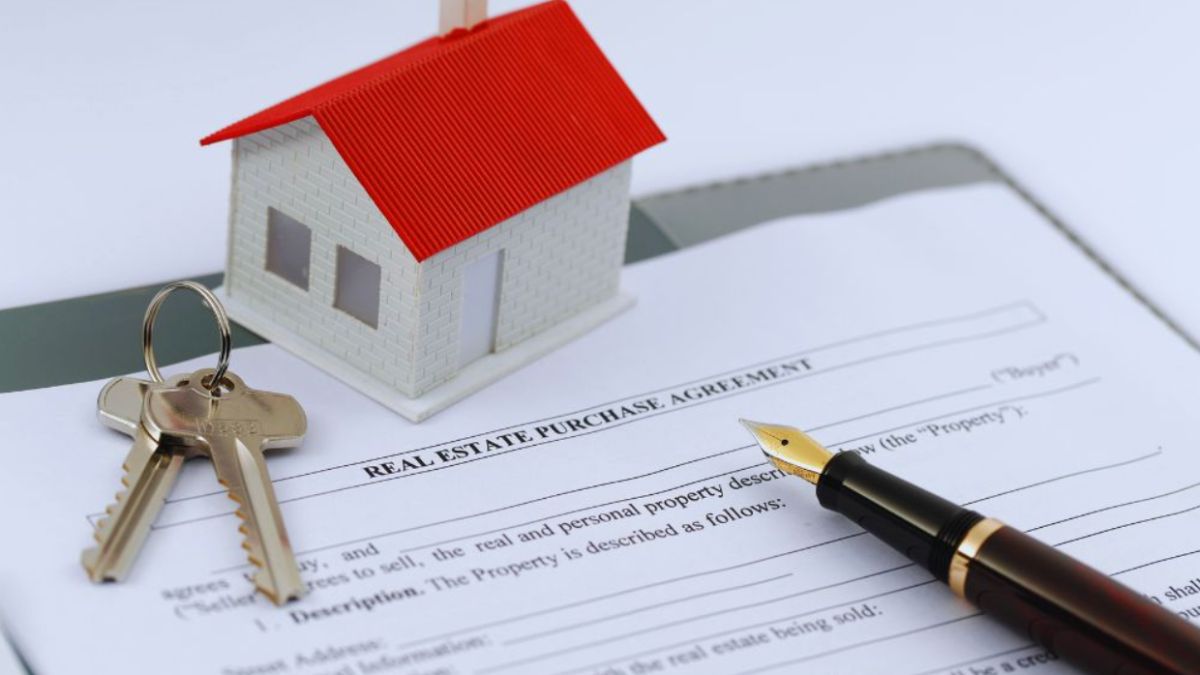 A real estate purchase agreement sits on a desk with a fountain pen, keys, and a model house, symbolizing the home-buying process.