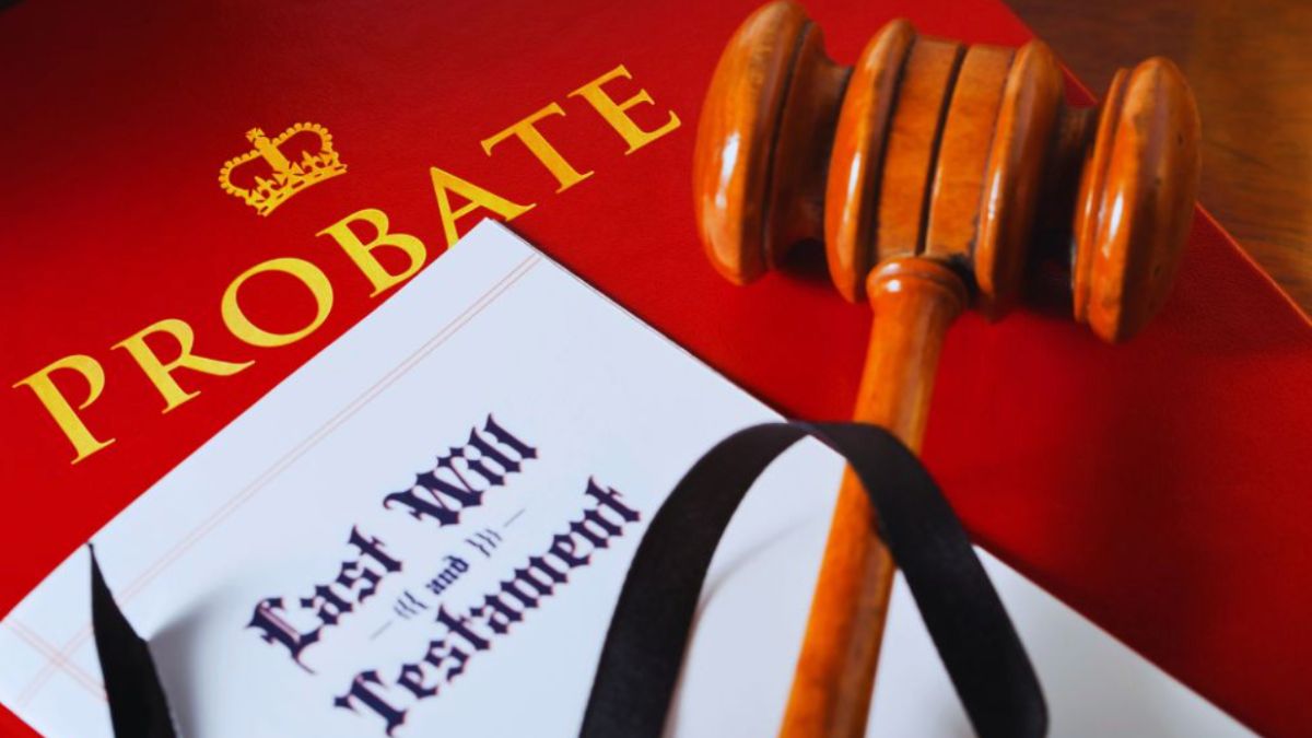 A judge’s wooden gavel lies on a red folder labeled “PROBATE,” next to a “Last Will and Testament” document tied with a black ribbon, representing the probate assets list and the legal process of identifying and distributing a deceased person’s estate