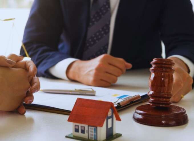 Attorney meeting with a client in Bluffton, SC, with legal documents, a gavel, and a house model representing wills, trusts, and asset planning.