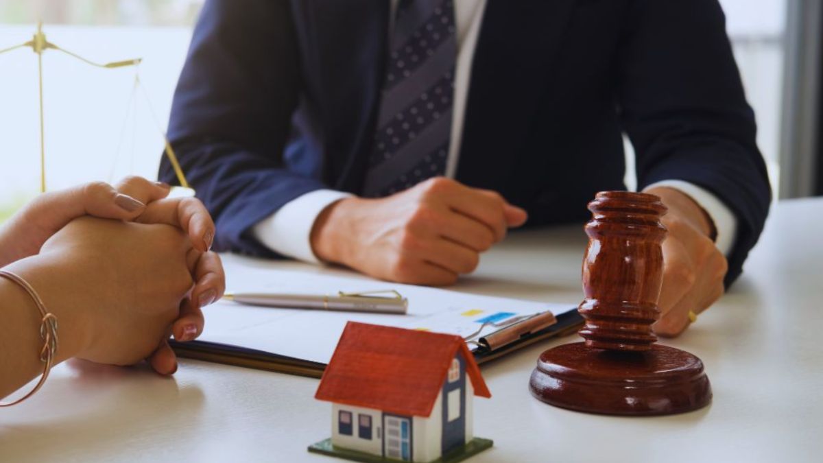 Real estate lawyer in Bluffton consulting with a client at a desk, with a judge’s gavel and model house representing legal support in property transactions.