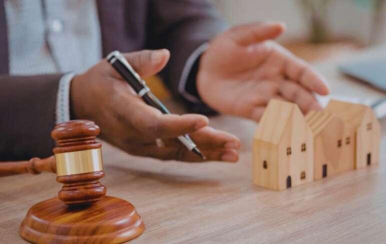 A real estate lawyer in Bluffton holds a gavel and a house model, emphasizing the legal side of real estate transactions.
