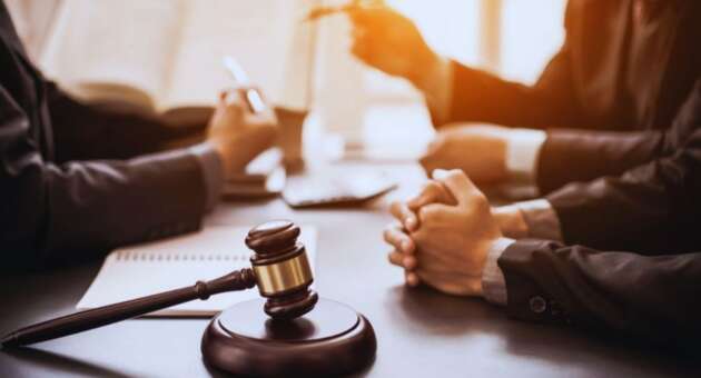 Close-up of a gavel on a desk during a meeting with a Bluffton business formation lawyer, with clients’ hands folded and legal documents open in the background.