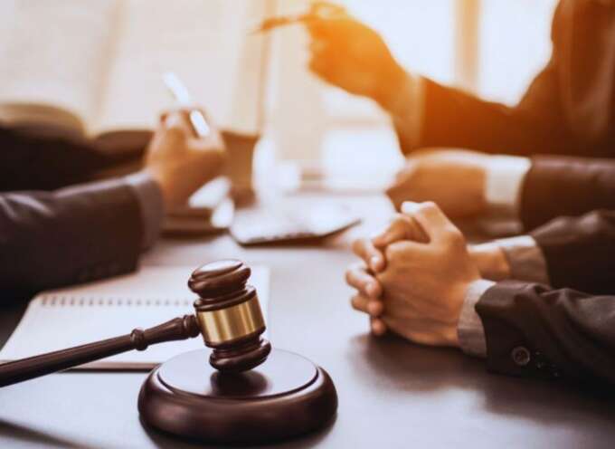 Close-up of a gavel on a desk during a meeting with a Bluffton business formation lawyer, with clients’ hands folded and legal documents open in the background.