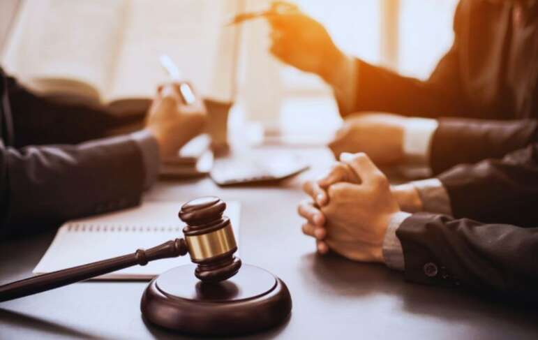 Close-up of a gavel on a desk during a meeting with a Bluffton business formation lawyer, with clients’ hands folded and legal documents open in the background.