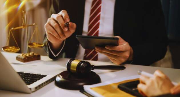Construction law attorney in Bluffton at a desk with a gavel, laptop, tablet, and scales of justice, reviewing case documents and advising a construction client.