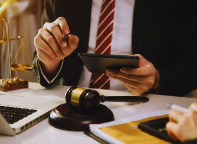 Construction law attorney in Bluffton at a desk with a gavel, laptop, tablet, and scales of justice, reviewing case documents and advising a construction client.