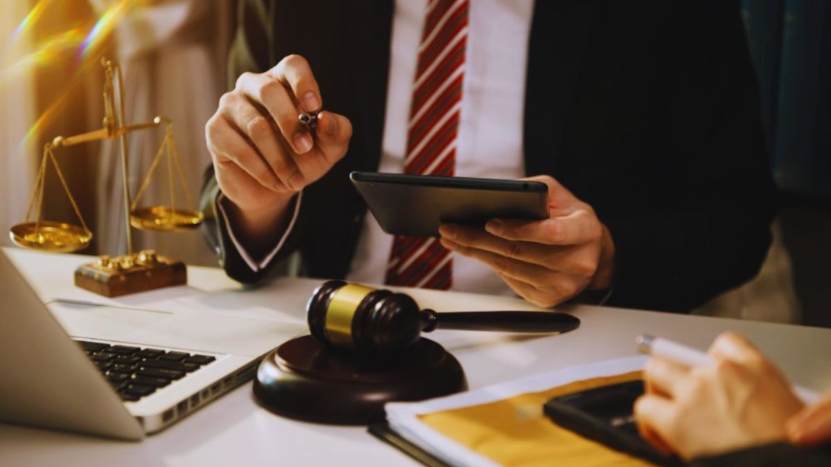 Construction law attorney in Bluffton at a desk with a gavel, laptop, tablet, and scales of justice, reviewing case documents and advising a construction client.
