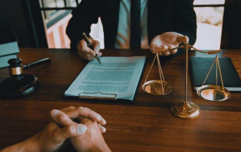 Contract law lawyer in Bluffton, SC reviewing a legal agreement with a client at a desk featuring a contract, gavel, and scales of justice.