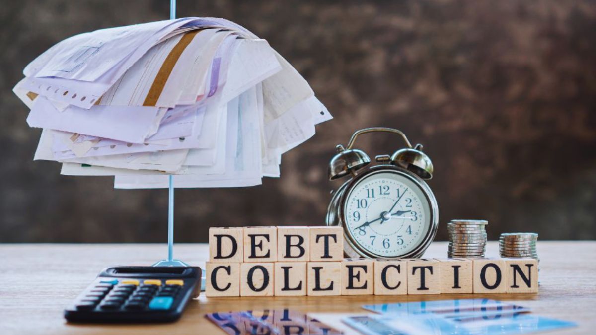 Debt collection concept with a stack of unpaid bills on a spike, a calculator, an alarm clock, stacks of coins, and wooden blocks spelling ‘DEBT COLLECTION’ on a desk, illustrating debt collection services in Bluffton.