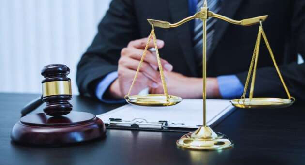 Collection lawyer seated at a desk with a gavel and scales of justice, reviewing documents related to debt collection and legal enforcement.