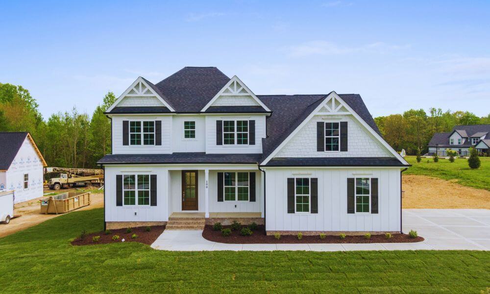 White two-story residential home with dark shutters representing real property probate assets in estate settlement process.