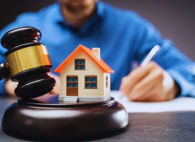 Property dispute attorney in South Carolina writing at a desk with a judge’s gavel and a small model house in the foreground, symbolizing legal help for real estate conflicts.