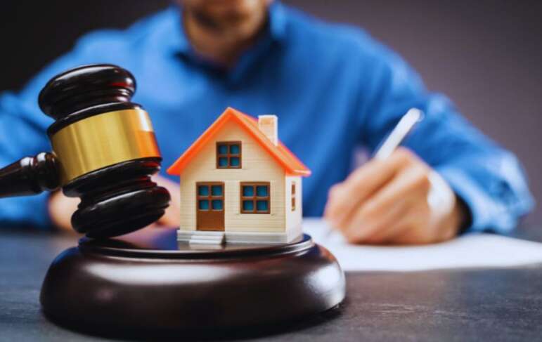 Property dispute attorney in South Carolina writing at a desk with a judge’s gavel and a small model house in the foreground, symbolizing legal help for real estate conflicts.