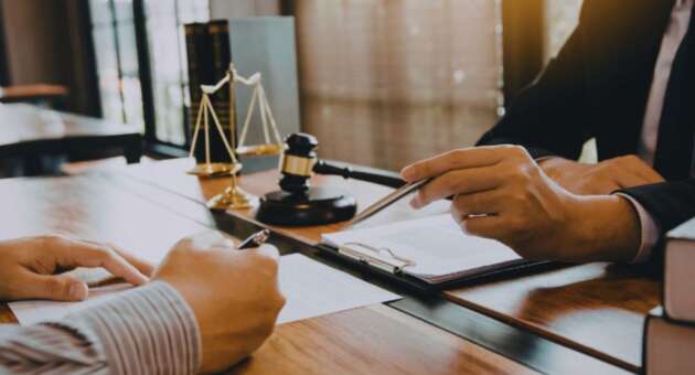 Contract lawyer reviewing legal documents with a client at a desk in a Hilton Head office.