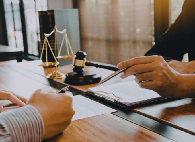 Contract lawyer reviewing legal documents with a client at a desk in a Hilton Head office.