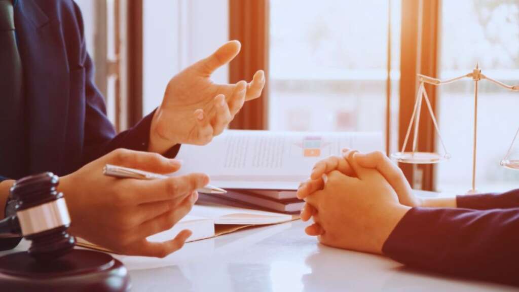 Debt collection attorney in Hilton Head discussing legal options with a client during a consultation, with legal documents, a gavel, and scales of justice on the desk.