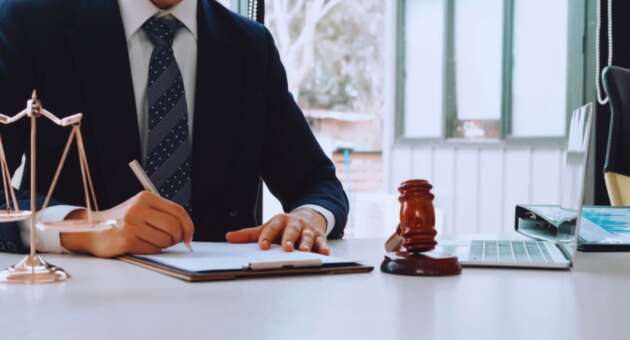 Debt collection attorney in Hilton Head, SC reviewing legal documents at a desk with a gavel, scales of justice, and laptop in a professional law office.