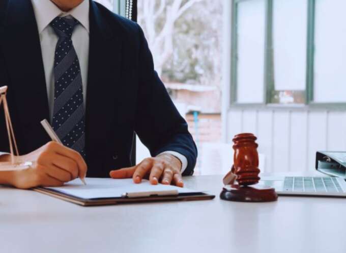 Debt collection attorney in Hilton Head, SC reviewing legal documents at a desk with a gavel, scales of justice, and laptop in a professional law office.