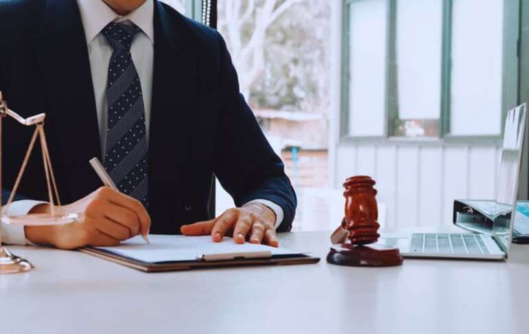 Debt collection attorney in Hilton Head, SC reviewing legal documents at a desk with a gavel, scales of justice, and laptop in a professional law office.
