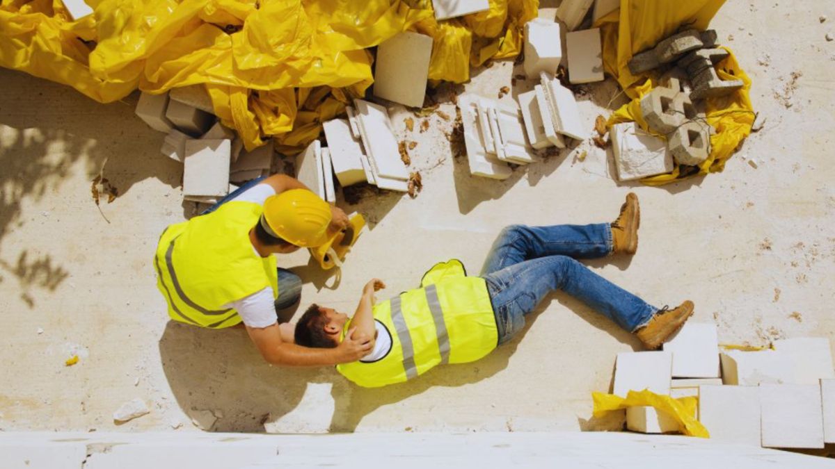 Injured construction worker lying on the ground at a Bluffton construction site while a coworker provides assistance, illustrating construction accidents and workplace injury claims.