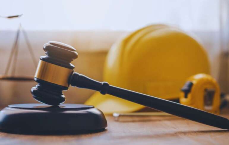 Judge's gavel with a construction hard hat and measuring tape in the background, representing legal services from a Bluffton construction accident lawyer for injured workers.