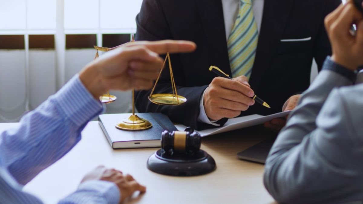 Attorney mediating a property dispute between two parties at a conference table, with scales of justice and a gavel visible.