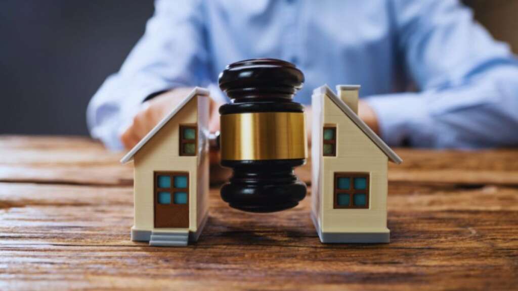 Judge’s gavel positioned between two model houses, representing property disputes and real estate legal matters.
