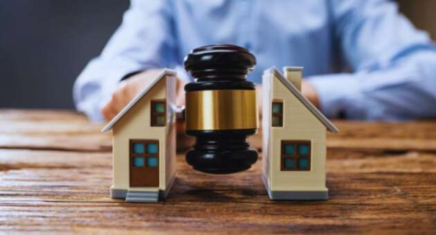 Judge’s gavel positioned between two model houses, representing property disputes and real estate legal matters.