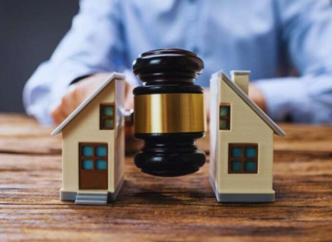 Judge’s gavel positioned between two model houses, representing property disputes and real estate legal matters.