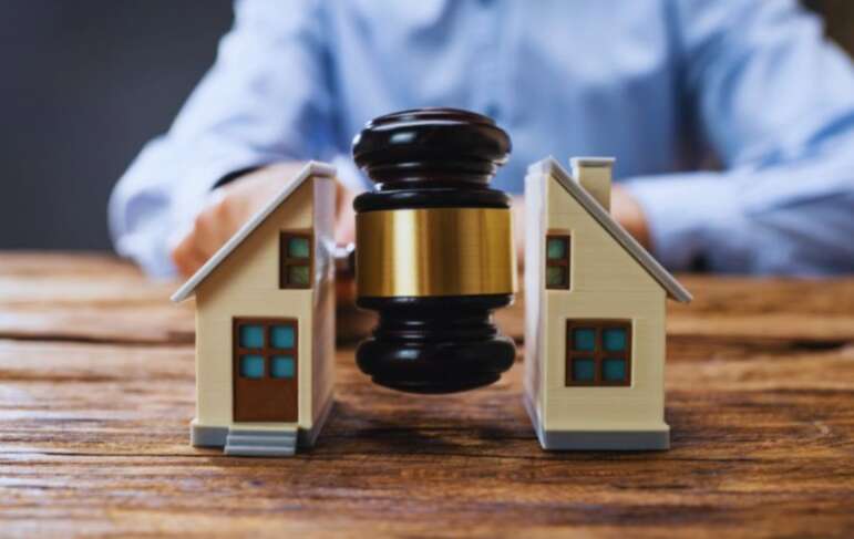 Judge’s gavel positioned between two model houses, representing property disputes and real estate legal matters.