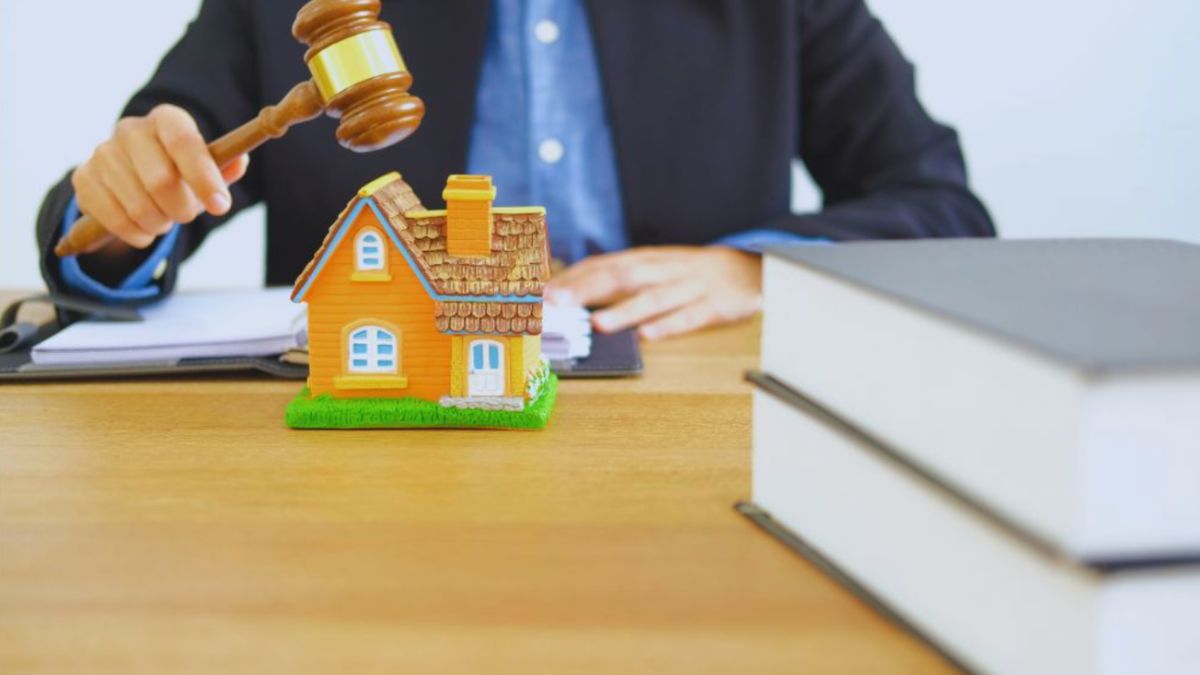 Property disputes lawyer holding a gavel beside a model house and legal books.