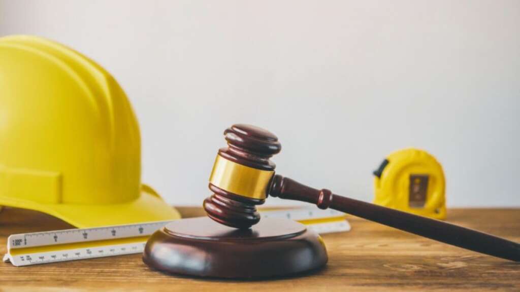 Construction litigation attorney’s gavel beside a yellow hard hat, measuring tools, and tape measure, symbolizing legal help with building disputes.