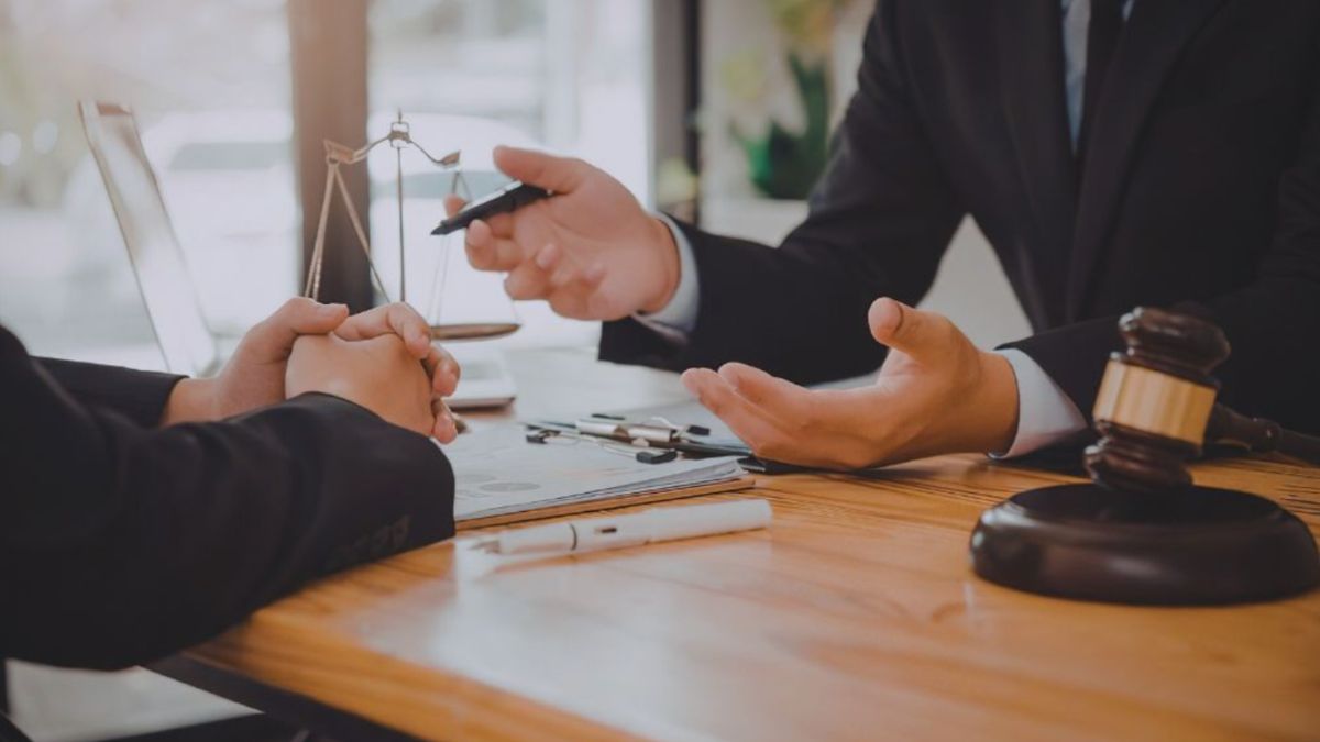 Construction litigation attorney consulting with a client at a desk with legal documents, scales of justice, and a gavel.